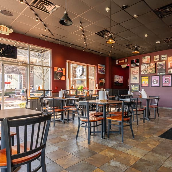 Interior of Oink And Moo BBQ, showing dining tables, chairs, and award-decorated walls.