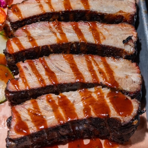 Close-up of Oink And Moo BBQ's saucy, tender pork ribs with a dark, smoky crust.