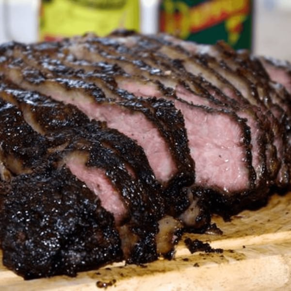 Close-up of sliced Oink And Moo BBQ brisket with a dark, smoky crust and pink interior.